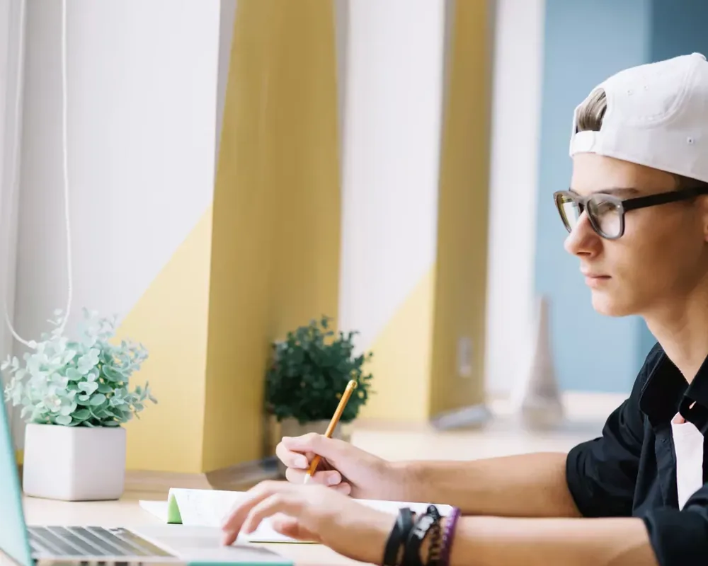 Online SAT özel dersinde laptopu başında not alarak çalışan bir öğrenci
