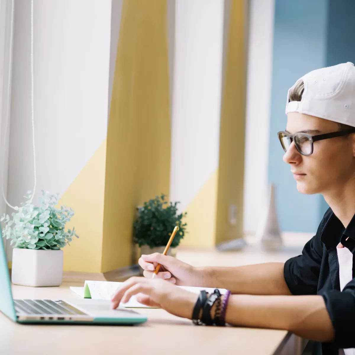 Online SAT özel dersinde laptopu başında not alarak çalışan bir öğrenci